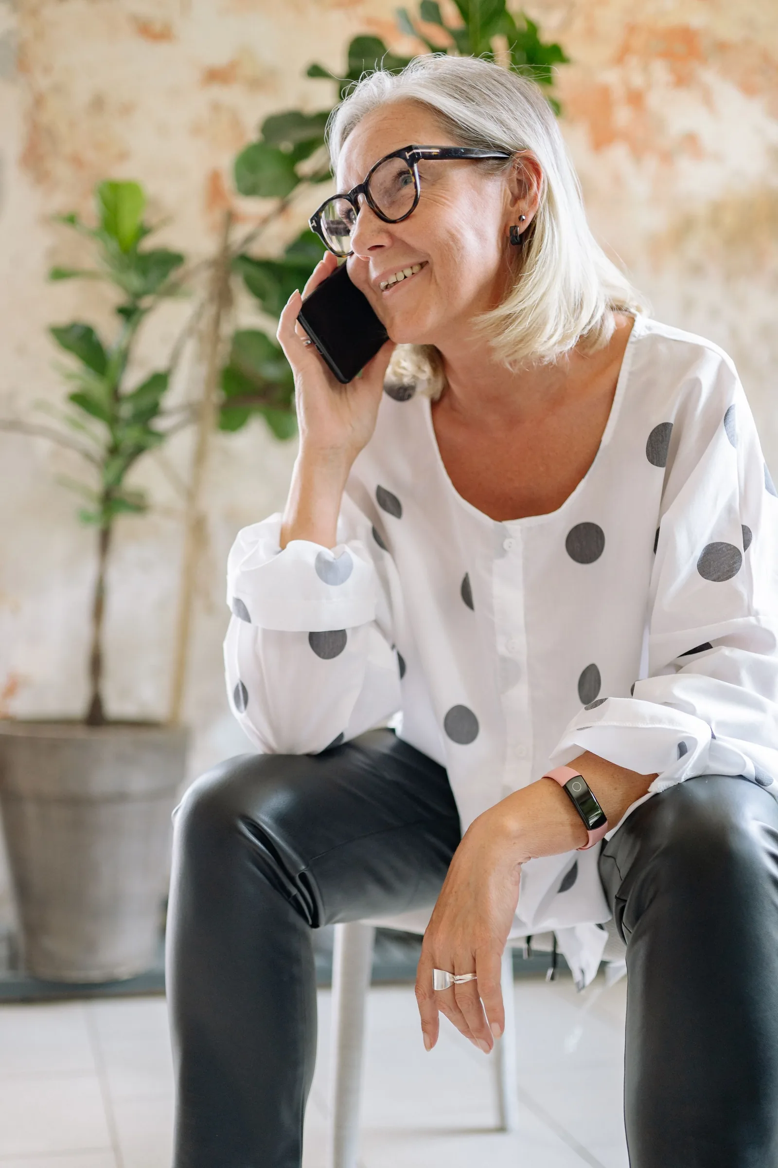 A smiling woman with glasses talking on a mobile phone.