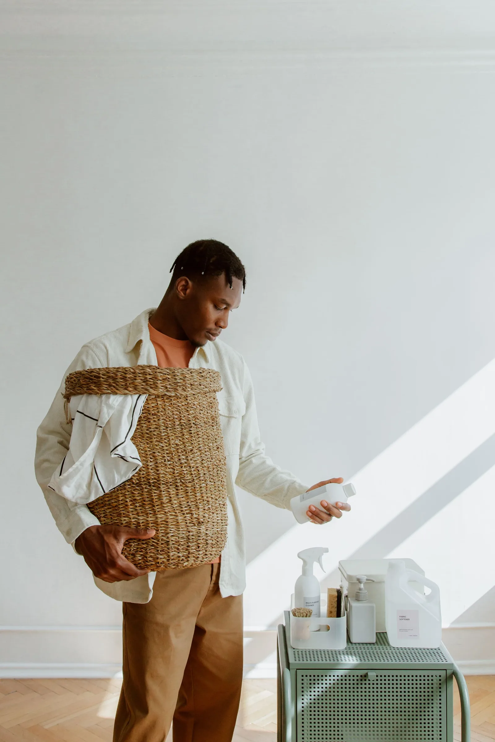 A man holding a laundry basket and looking at a cleaning product.